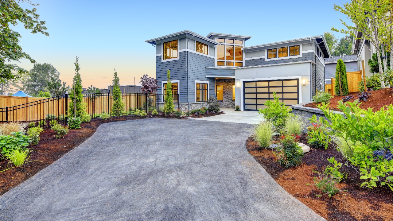 A driveway leading to a garage surrounded by beautiful landscaping.